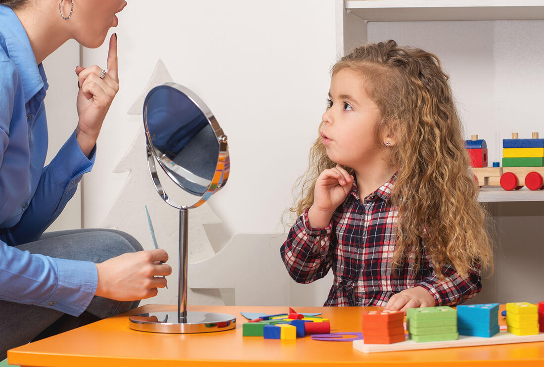 Speech Therapist using a mirror to work with child